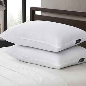 A pair of white Eddie Bauer jumbo pillows with a smooth finish, stacked on a bed. They feature a small black tag on the side, indicating brand details.