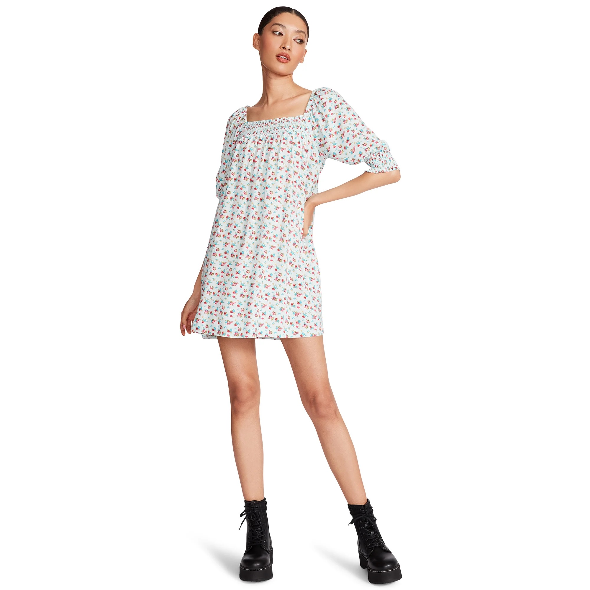 A woman is wearing a floral print dress with three-quarter sleeves and black lace-up boots.