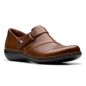 Brown Clarks Ashland slip-on shoes feature leather uppers with textured detailing, a subtle strap with button accent, and a black cushioned sole for comfort.
