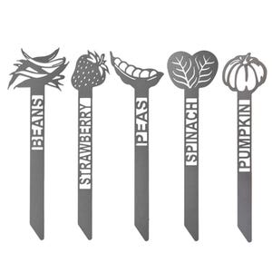 Garden plant markers for beans, strawberry, peas, spinach, and pumpkin, each featuring a cutout design of the respective plant above the name.