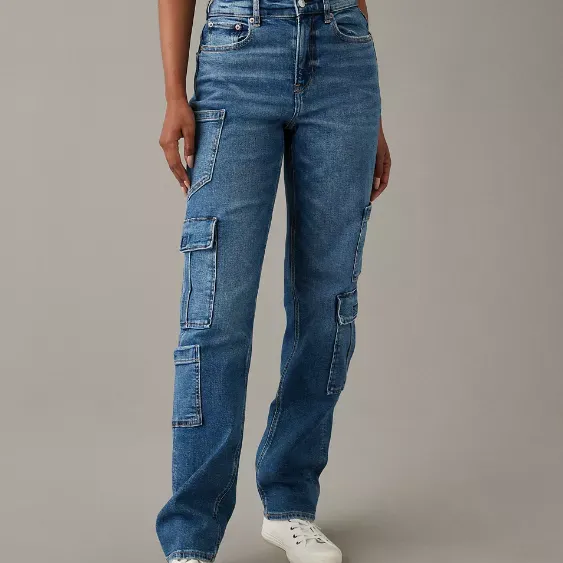 Blue cargo-style jeans with multiple pockets, paired with a black crop top and white sneakers.