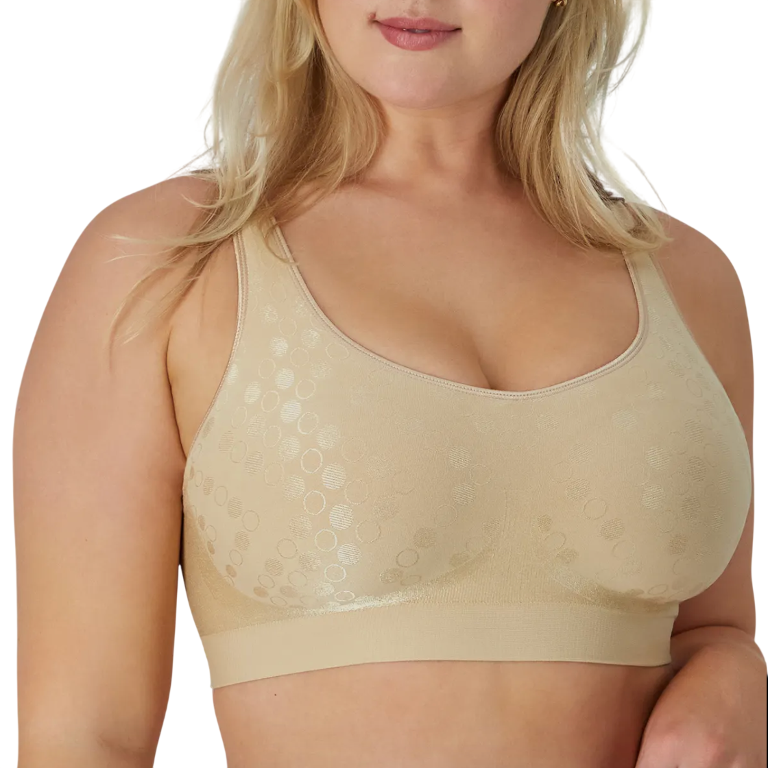 A woman wears a beige bra with a subtle circular pattern, featuring wide straps and a seamless design, providing full coverage and support.