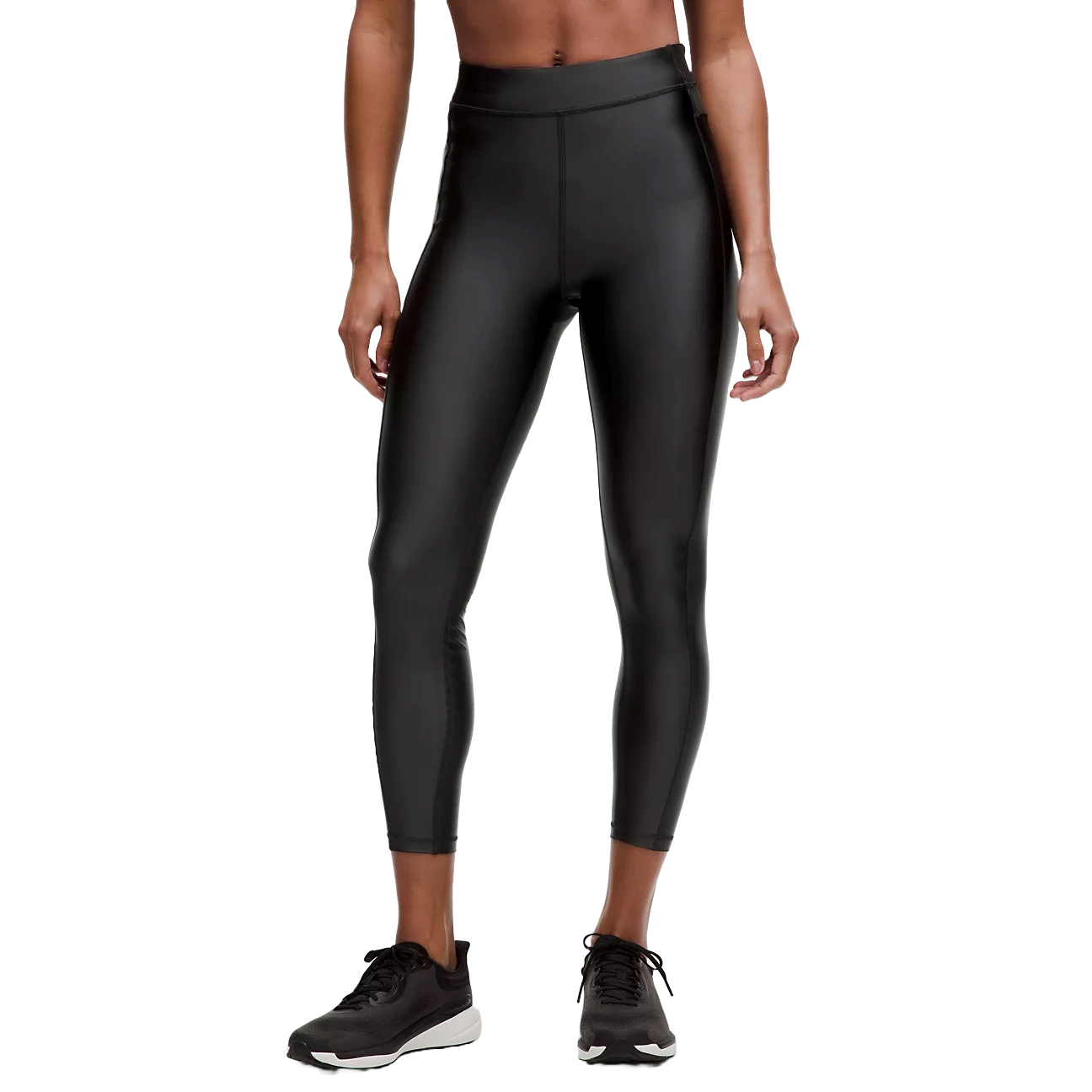 A person is wearing shiny black high-waisted leggings paired with black running sneakers.