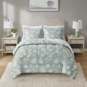 A queen comforter set with a pale green botanical print, including a comforter and two matching pillow shams, displayed on a bed with a neutral headboard and flanked by matching bedside tables with lamps.