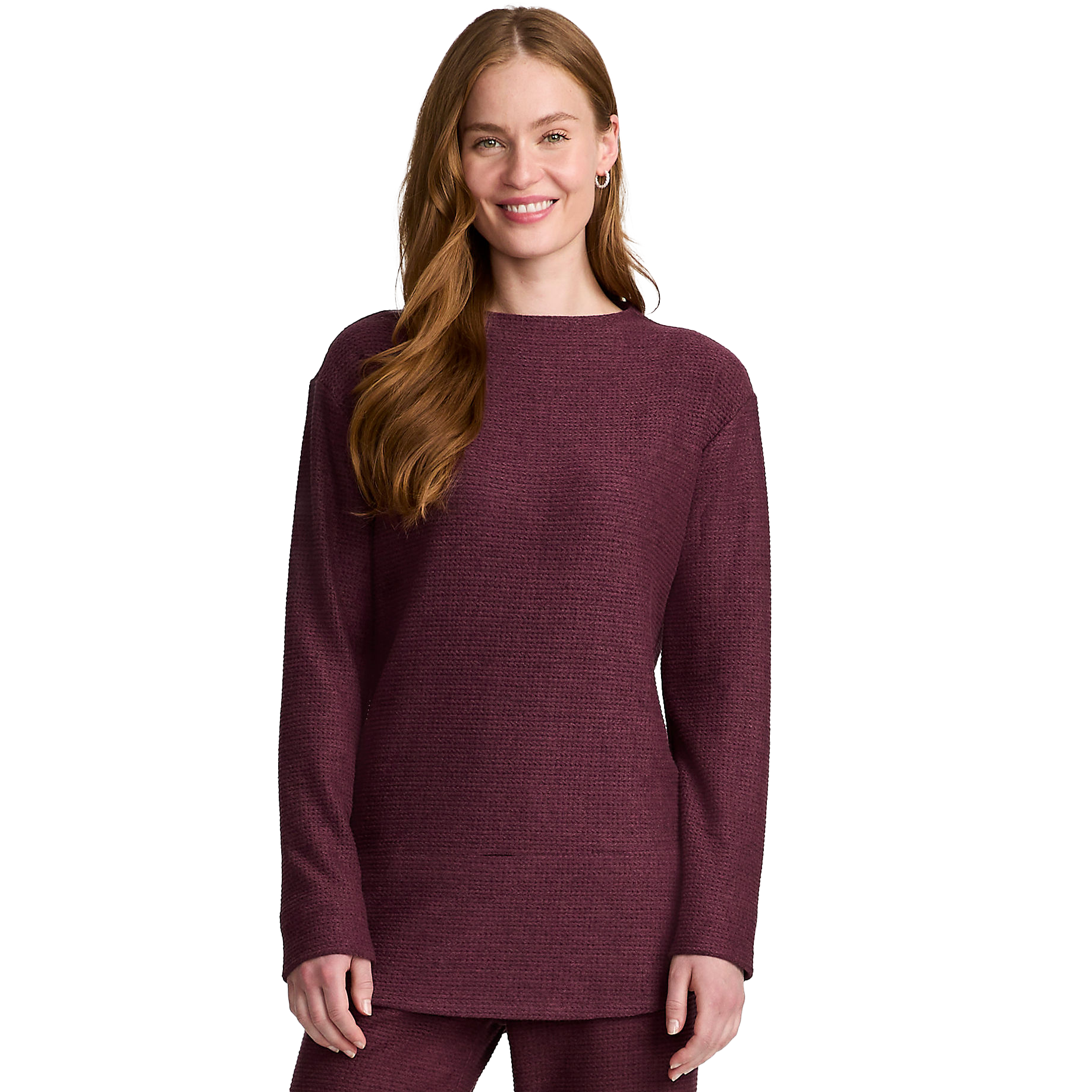 A woman models a relaxed-fit, long-sleeve tunic in a textured, dark burgundy knit fabric. The tunic features a simple round neckline and a straight hemline.