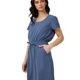 A woman is wearing a blue, short-sleeved dress with a cinched waist, side pockets, and a round neckline.