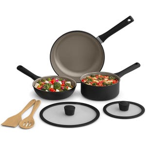 Cookware set with black handles, including two pots with lids, a frying pan, and two wooden utensils. Contains colorful food items like vegetables inside the cookware.