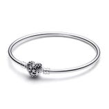 A silver bangle bracelet featuring a heart-shaped charm with star and moon cutouts.