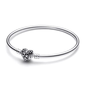 A silver bangle bracelet featuring a heart-shaped charm with star and moon cutouts.