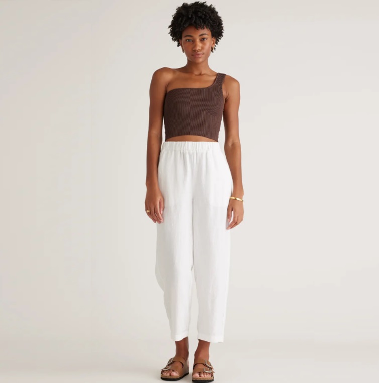 A woman models a brown cropped tank top, white wide-leg cropped pants, and brown strappy sandals.