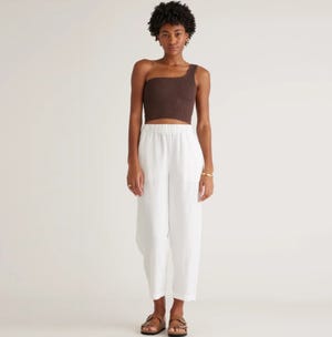 A woman models a brown cropped tank top, white wide-leg cropped pants, and brown strappy sandals.