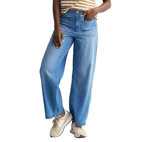 Woman wearing light blue wide-leg jeans, paired with a striped top and beige sneakers.