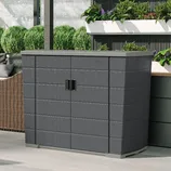 A black outdoor storage cabinet with double doors is placed on a patio, surrounded by plants and outdoor furniture.