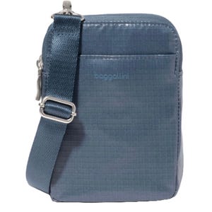 A compact, dark blue crossbody bag with an adjustable strap and a subtle grid pattern. Features a front pocket and metal hardware, with \“baggallini\“ branding on the front.