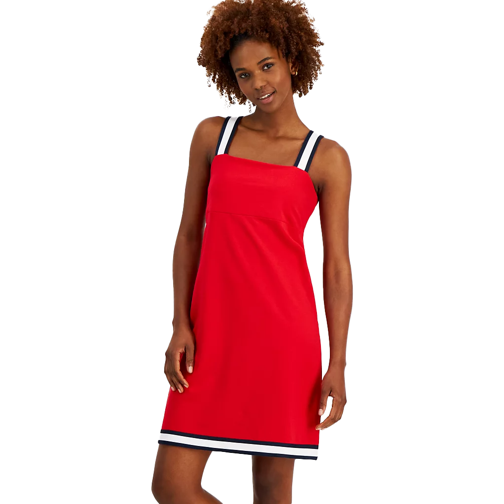 A woman is wearing a red tank dress with contrasting white and navy trim at the edges.