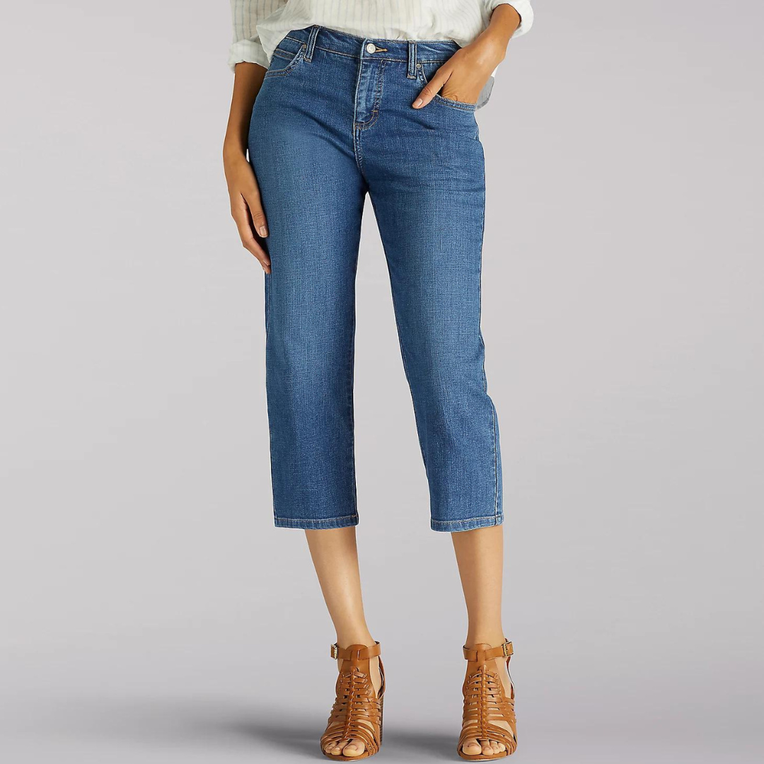 A person is wearing cropped blue denim jeans and brown strappy sandals.