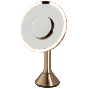 Round, illuminated tabletop mirror with a bronze-colored base and frame.