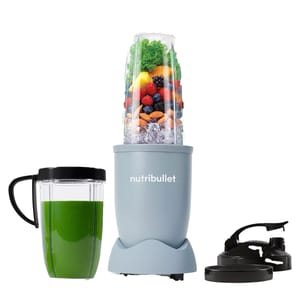 The NutriBullet Pro 900w Blender includes a base with a blending cup full of fruits, nuts, and ice, a separate cup with a green smoothie, and two lids. The blender is designed for making smoothies and blending a variety of ingredients.