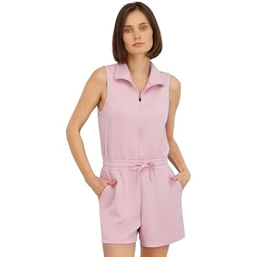 A woman is wearing a sleeveless, light pink romper with a zipper front and drawstring waist, featuring side pockets.