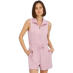 A woman is wearing a sleeveless, light pink romper with a zipper front and drawstring waist, featuring side pockets.