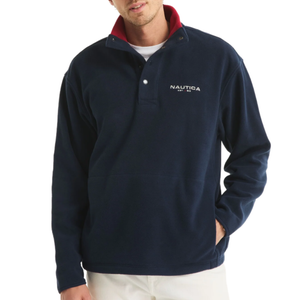 A navy fleece pullover with a red collar and buttoned placket, featuring the Nautica logo on the chest, paired with white pants.