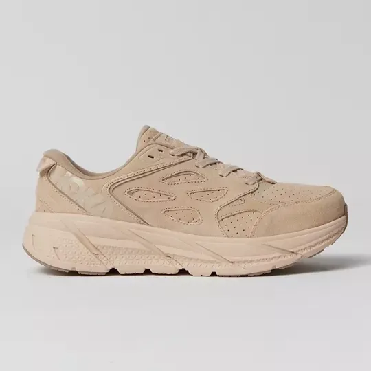 A single beige sneaker with thick soles and a swirled design pattern on the side.