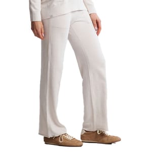 A person is wearing loose-fitting, white pants paired with brown shoes, suitable for a casual or cozy look.