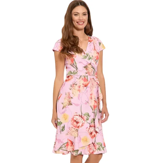 A woman is wearing a pink floral knee-length dress with short sleeves and a V-neckline, paired with tan high-heeled sandals.
