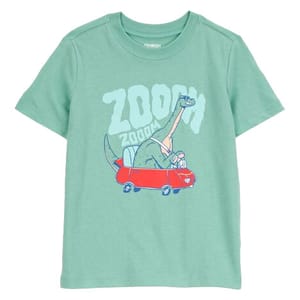 A light green children's T-shirt features a cartoon dinosaur driving a red car with the word \“ZOOM\“ above it.