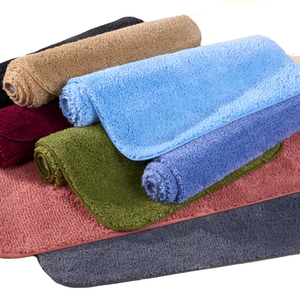 Rolled and flat bath mats in various colors, including blue, green, red, and beige. Made from soft, absorbent material.
