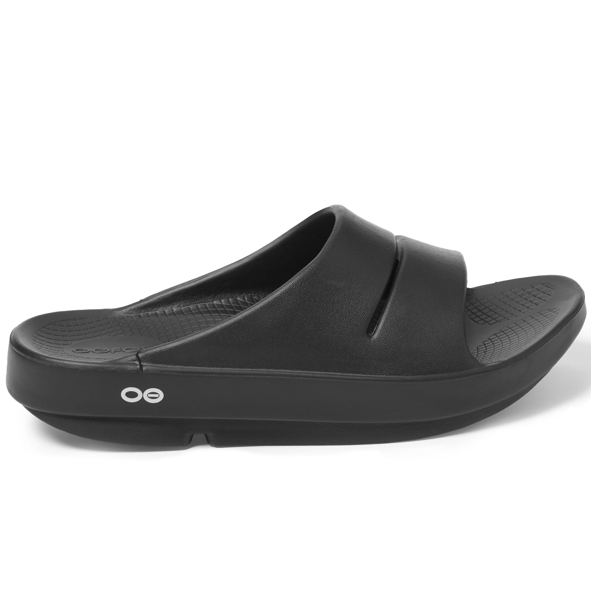Black Oofos OOahh Slides with a thick, contoured footbed, slip-on design, and a wide single strap featuring subtle ventilation slits. The sole has a textured pattern for grip and comfort.
