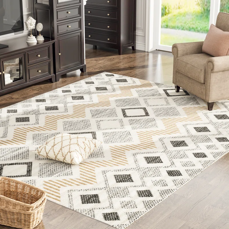 A 5' x 8' area rug features a geometric chevron pattern in neutral shades of beige, black, and white, with a decorative pillow on top.
