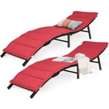 Two stackable folding lounge chairs with curved designs and red cushioned surfaces. They feature sturdy frames and include a multi-colored pillow and a blanket for added comfort.