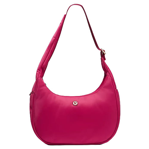 A pink shoulder bag with a structured, crescent shape, featuring a small circular logo on the front.