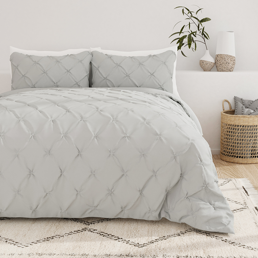 A neatly made bed with a gray tufted comforter set paired with matching pillows, placed in a room with decorative items.