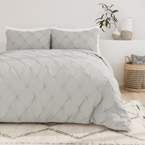 A neatly made bed with a gray tufted comforter set paired with matching pillows, placed in a room with decorative items.