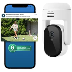 Smartphone displaying a notification from Arlo security camera, showing a person identified as \“Nicole\“ in the backyard. An Arlo security camera is positioned next to the phone with \“6 Months of Arlo Plus Features Included.\“