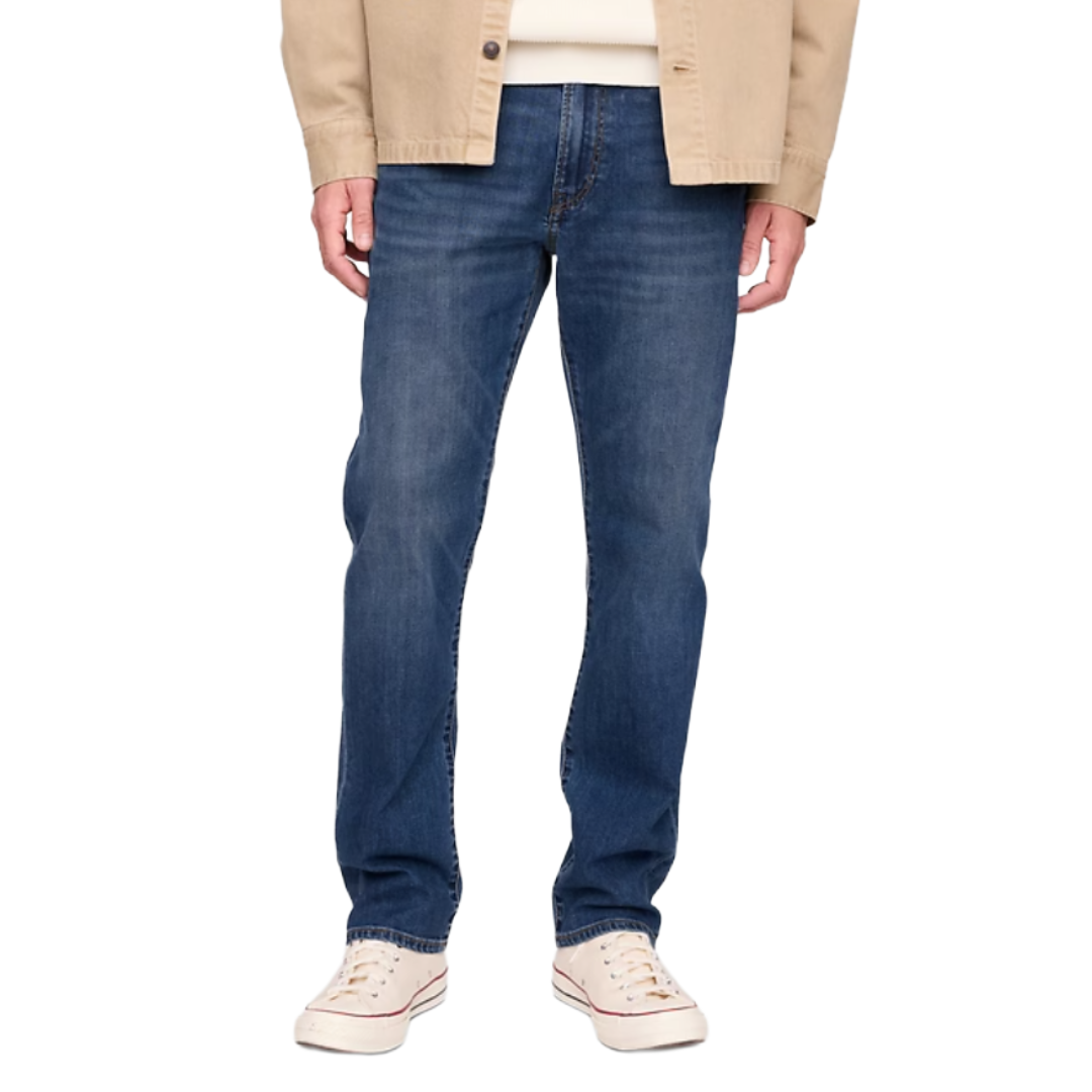 A person is wearing blue straight-leg jeans paired with white sneakers and a beige jacket.