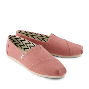 Pink slip-on shoes with a textured fabric upper and beige soles, featuring a black and white chevron pattern inside.