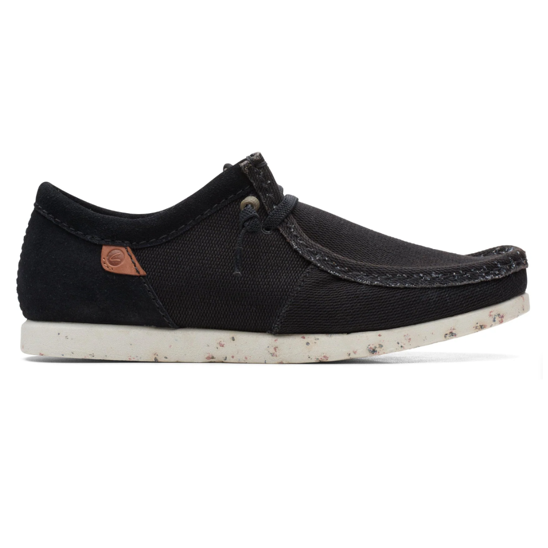 A black casual shoe with a textured fabric upper, suede accents, white sole with speckles, and a simple lacing system.