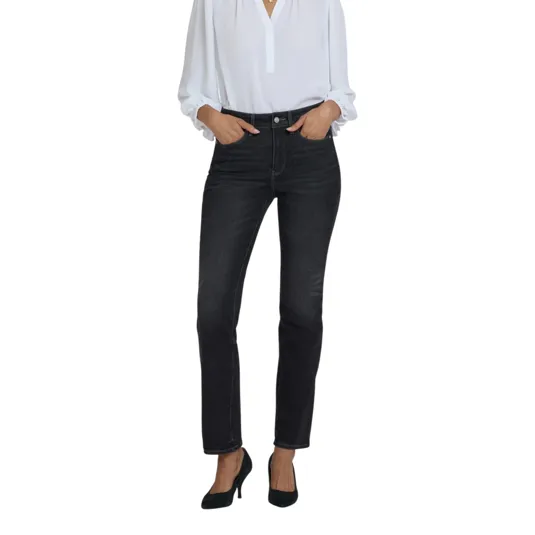 A woman wearing a white long-sleeve blouse, dark high-waisted jeans, and black heels.