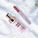 Braid Balm by UNBEACHWAVER (pre-braid prep, 118 ml) and Tarte Maracuja Juicy Lip Wand are displayed on a snowy background with pine branches.