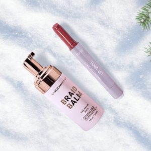 Braid Balm by UNBEACHWAVER (pre-braid prep, 118 ml) and Tarte Maracuja Juicy Lip Wand are displayed on a snowy background with pine branches.