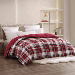 A bed features a red and white plaid comforter with several white pillows against a beige headboard. A gold floor lamp and minimalist shelves in the background add modern decor elements to the room.