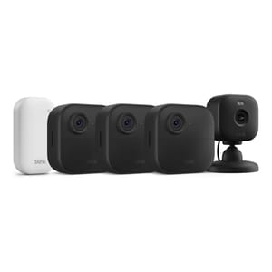 A set of Blink security cameras and a module, including three black outdoor cameras and one black indoor camera on a stand, along with a white sync module.