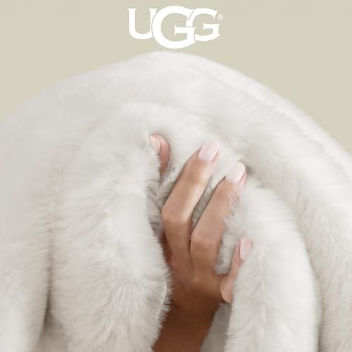 A hand grips a fluffy, white UGG blanket, conveying its softness and warmth.