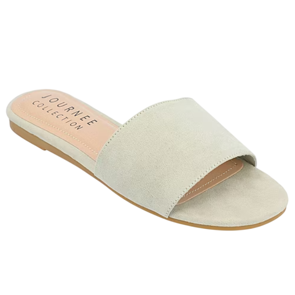 A light beige slide sandal from Journee Collection, featuring a wide suede strap and a flat sole.