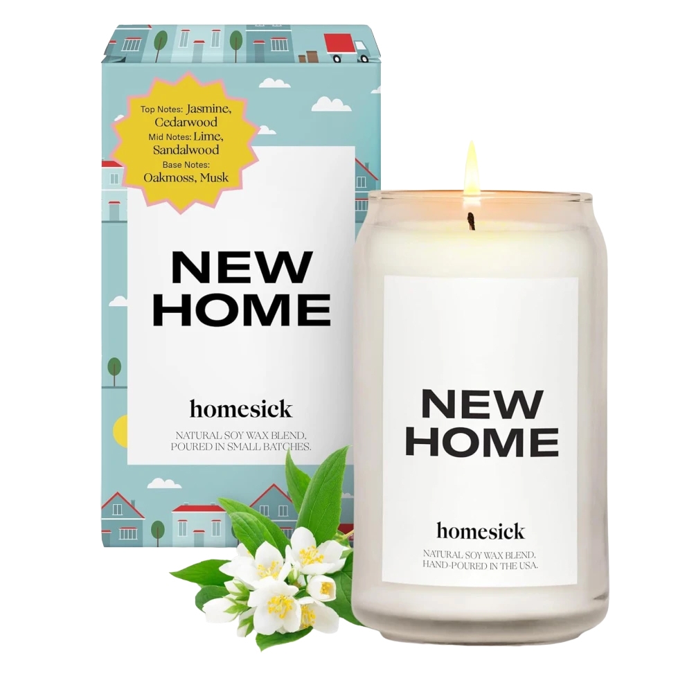 Homesick Soy Wax Candle labeled \“New Home\“ with scent notes of jasmine, cedarwood, lime, sandalwood, oakmoss, and musk. Comes in a glass jar and features packaging with house illustrations.