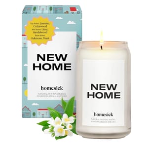 Homesick Soy Wax Candle labeled \“New Home\“ with scent notes of jasmine, cedarwood, lime, sandalwood, oakmoss, and musk. Comes in a glass jar and features packaging with house illustrations.