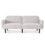 A minimalist white upholstered convertible futon sleeper bed with a split-back design, rounded armrests, and wooden legs.